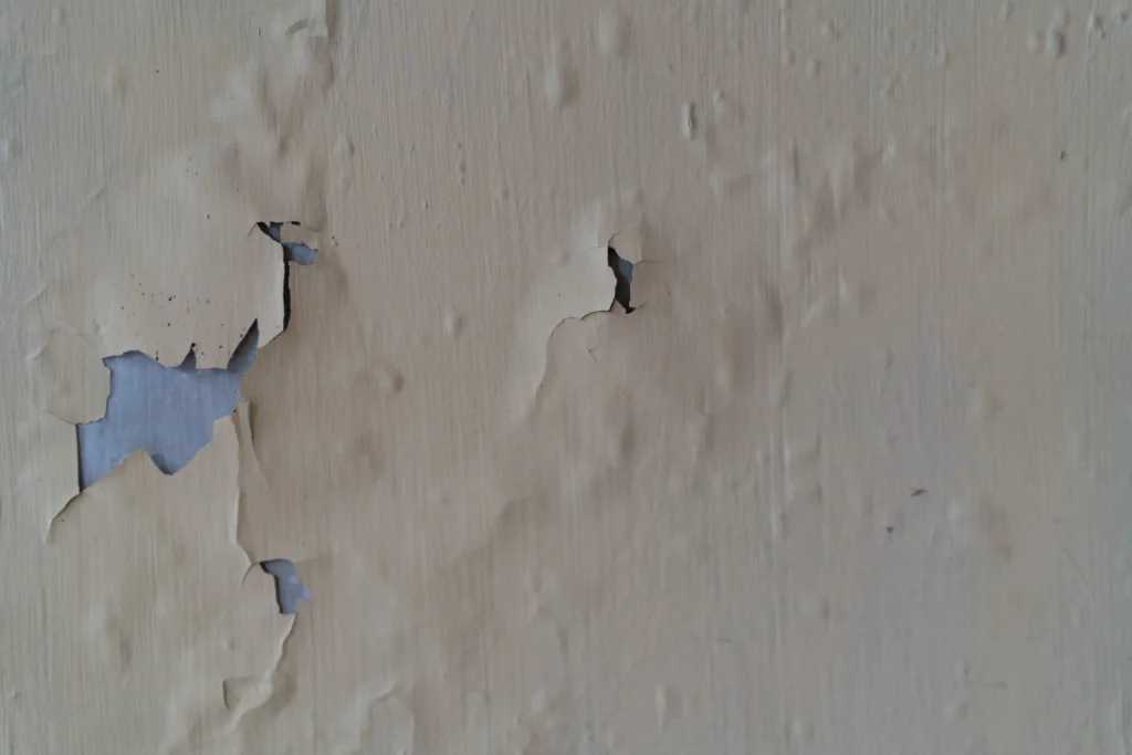 Interior wall with peeling paint before repainting by a painting company.